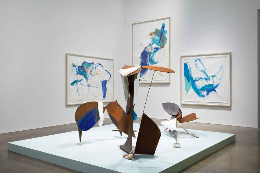 Installation view of Ro Robertson in 'Trickster Figures: Sculpture and the Body': in the foreground, a series of sculptural objects, in the background, three framed works on paper.